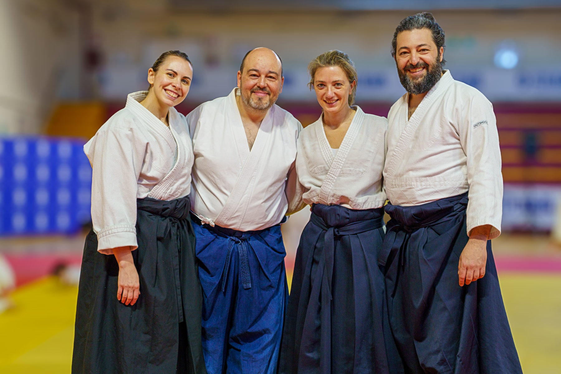 Quattro istruttori di aikido in hakama sorridono in palestra