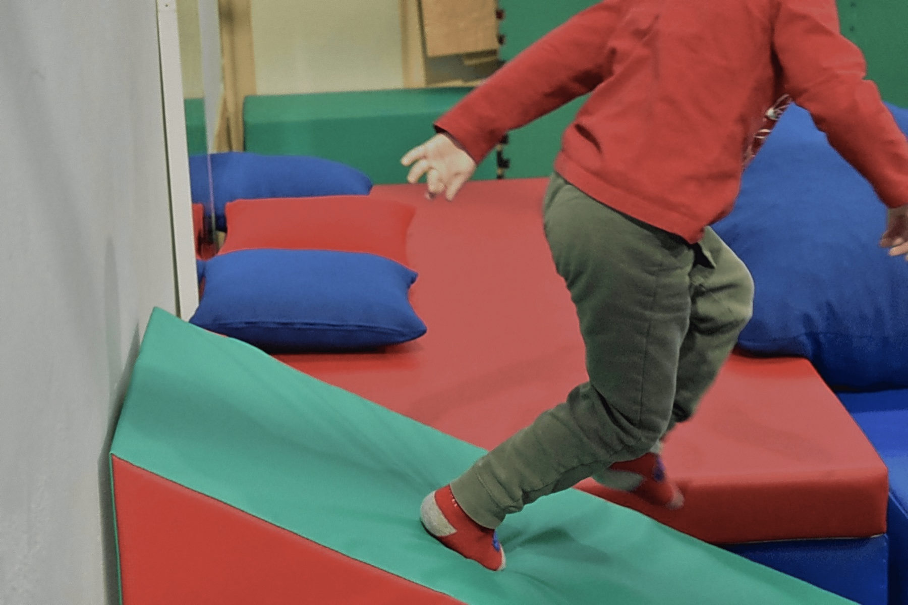 Un bambino salta sui materassi colorati della sala di psicomotricità