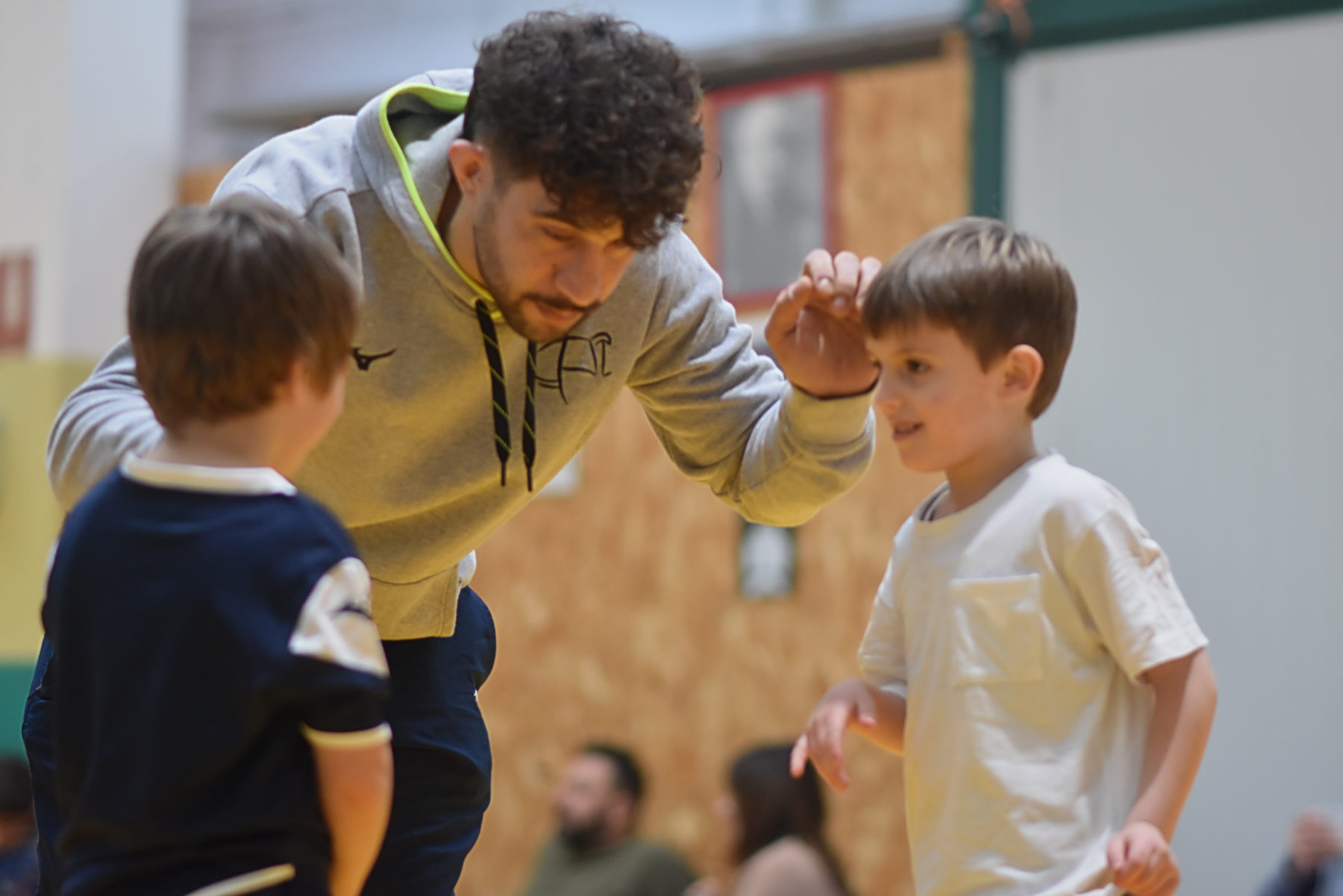 Un istruttore di lotta con due bambini piccoli sul tappeto