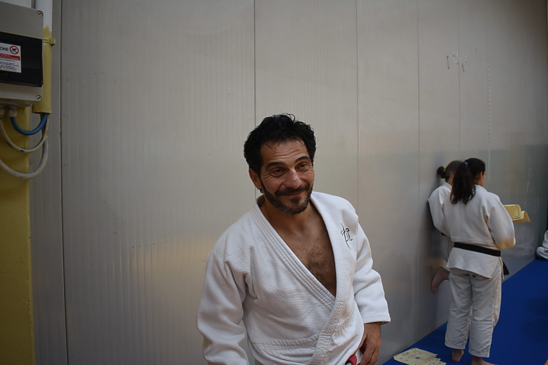 Un istruttore di judo sorride in kimono bianco in palestra